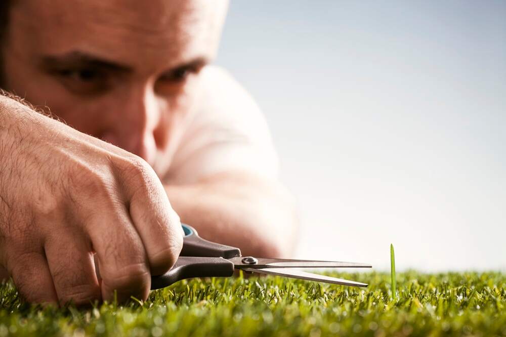 Man cutting blade of grass in example of maladaptive perfectionism