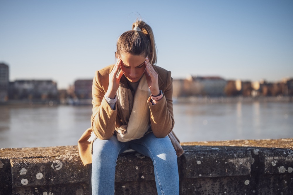 woman with retroactive jealousy sitting by a city reservoir